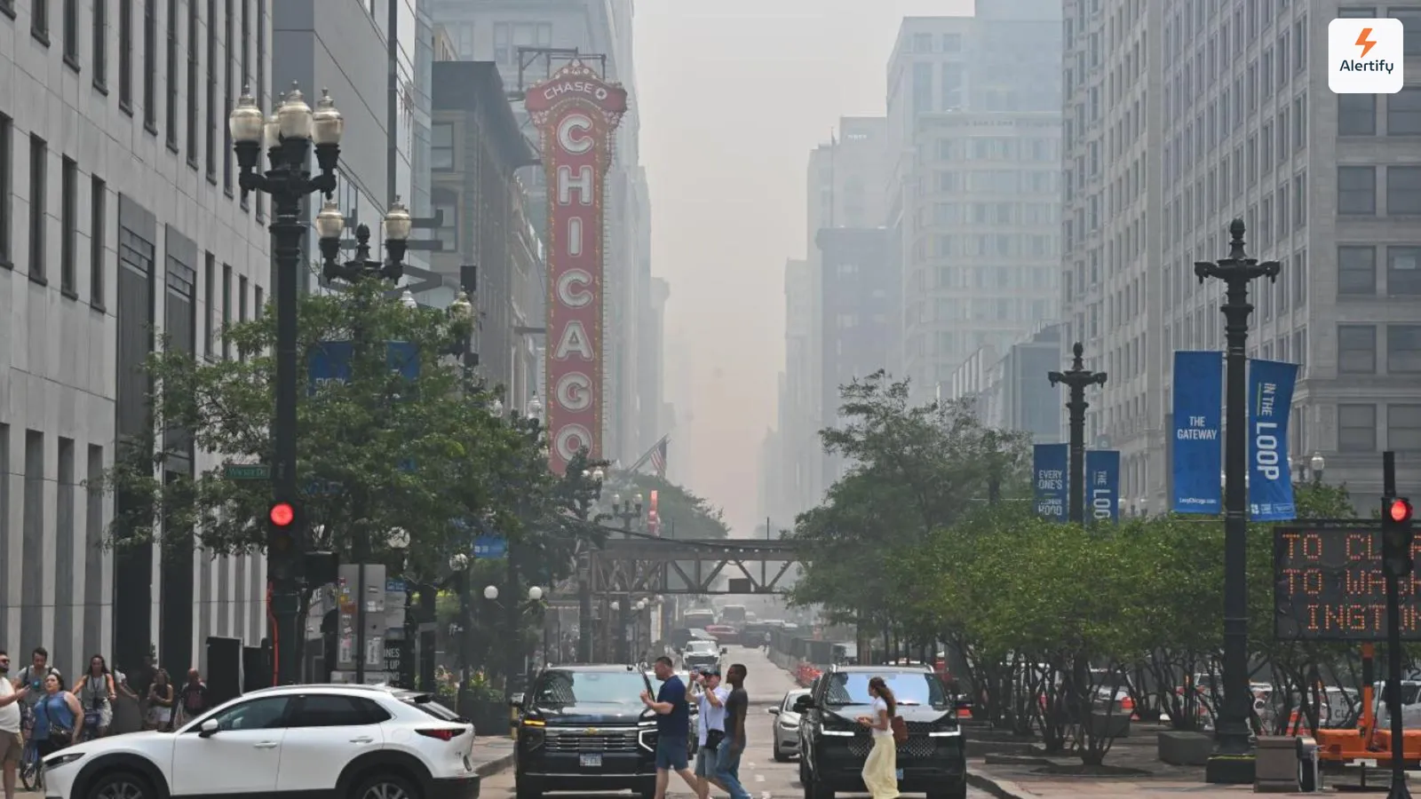 Neblina de incendios forestales envolviendo los edificios de una calle de Chicago, con el letrero del Chicago Theatre iluminado en primer plano.