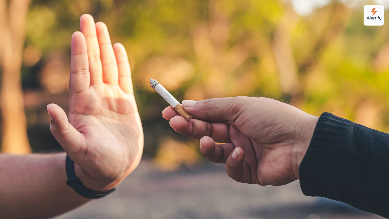 Mano levantada para rechazar educadamente un cigarrillo encendido ofrecido por otra persona en el exterior