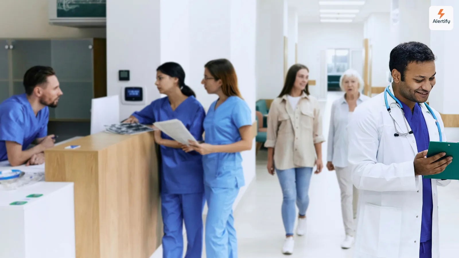 Personal clínico y visitantes pasando junto al mostrador de recepción en un luminoso vestíbulo de hospital