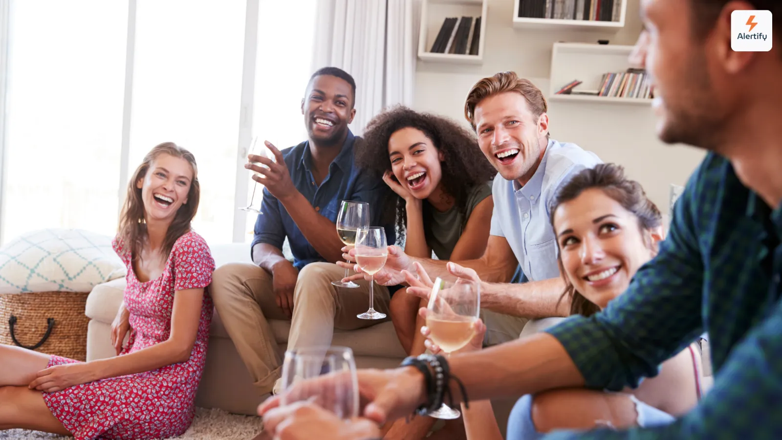 Grupo de amigos riendo con copas de vino en el salón de un alquiler vacacional