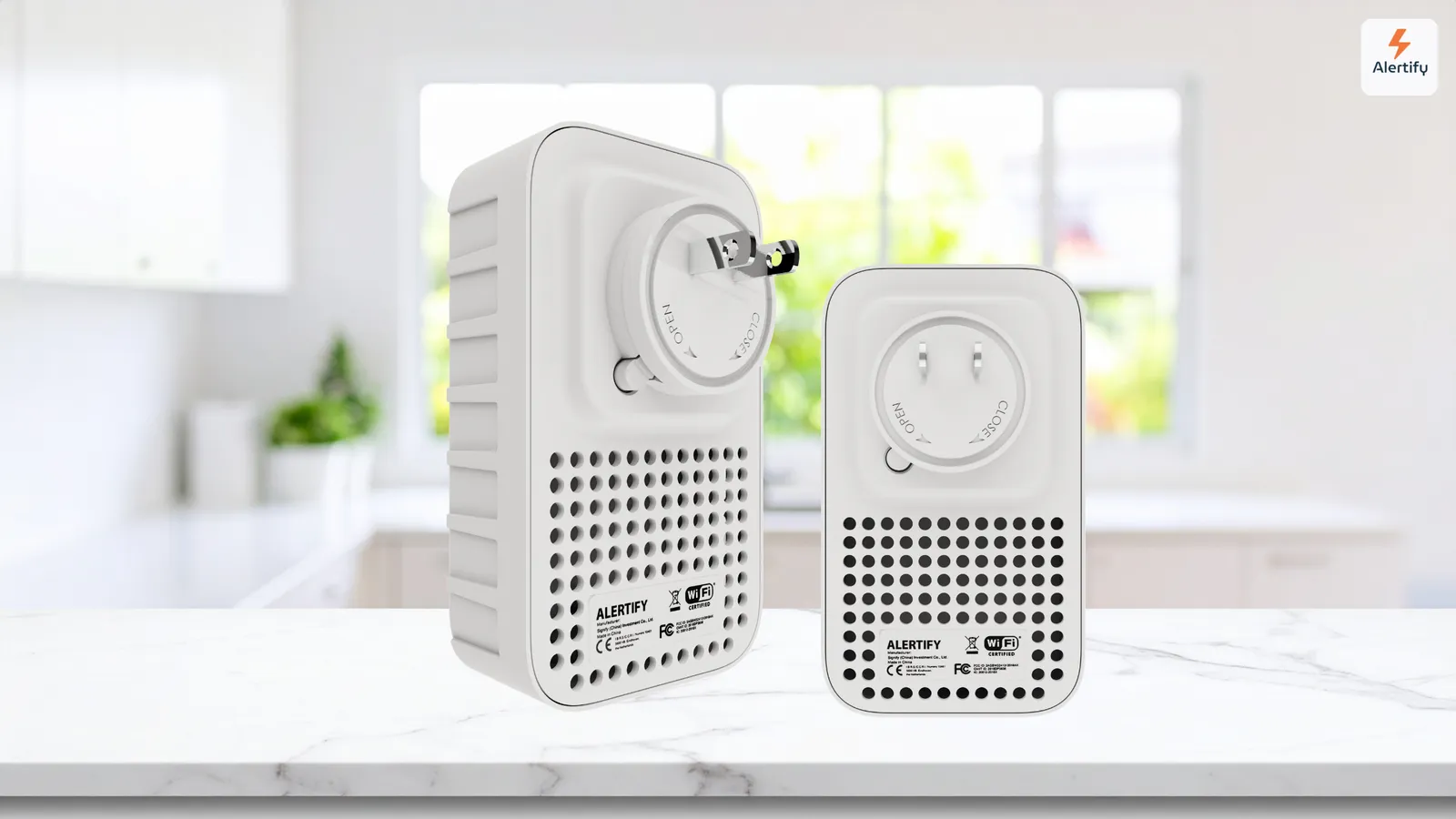 Dos dispositivos de monitorización enchufables de Alertify, la unidad más grande apta para exteriores y la más pequeña para interiores, uno junto al otro sobre la encimera de una cocina.
