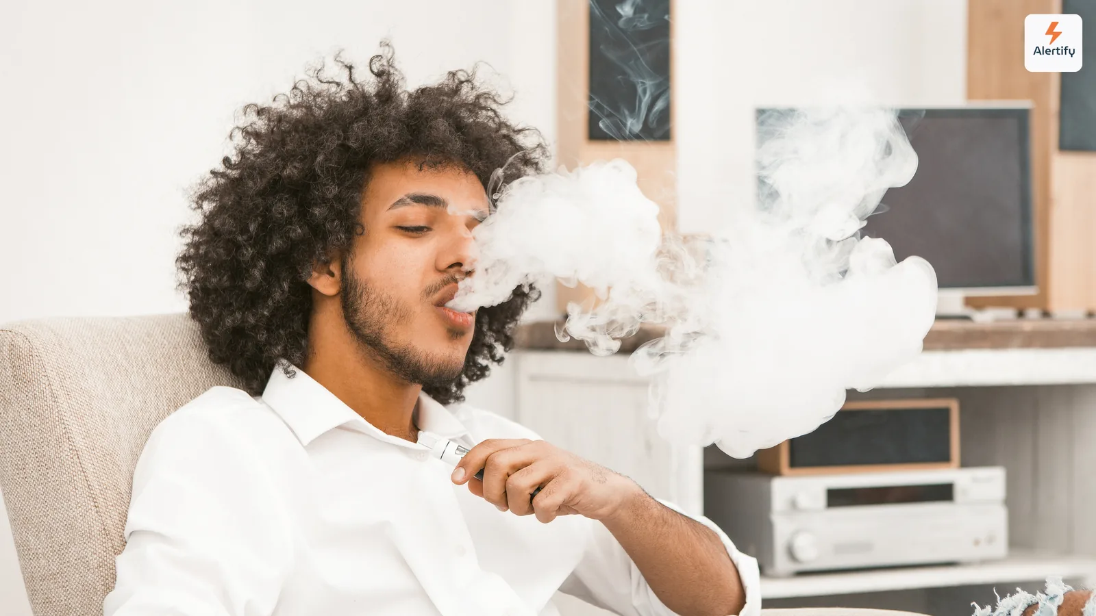Huésped exhalando una densa nube de vapor sentado en el salón de un alquiler vacacional